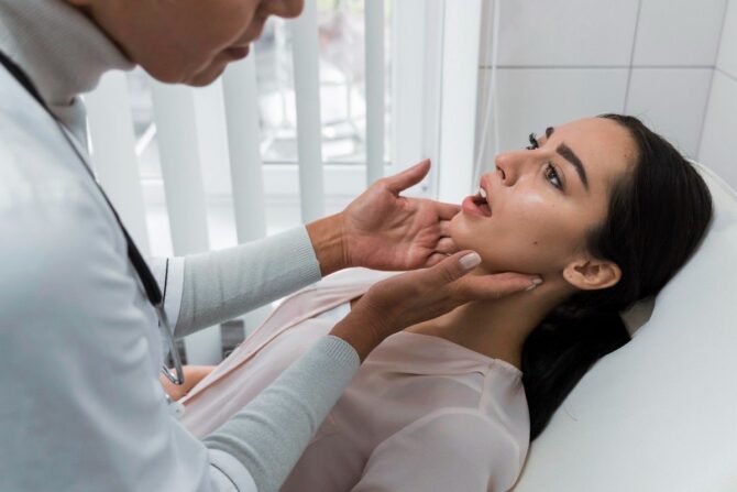 Dentist examining a woman’s jaw during a dental checkup.