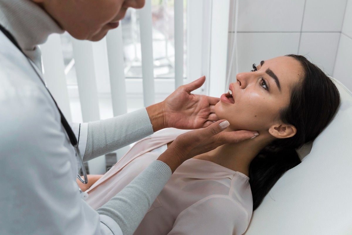 Dentist examining a woman’s jaw during a dental checkup.