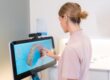 Dentist reviewing a 3D digital scan of teeth on a touchscreen monitor in a modern dental clinic