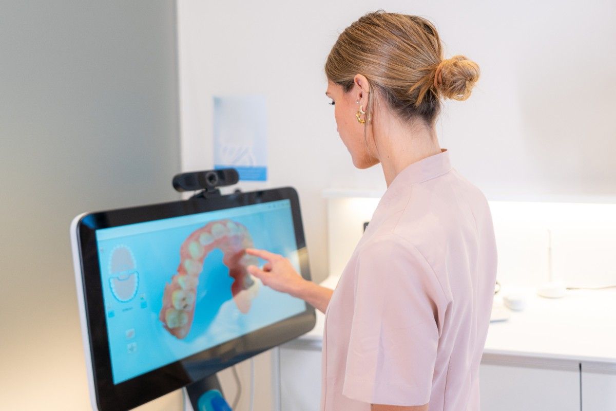Dentist reviewing a 3D digital scan of teeth on a touchscreen monitor in a modern dental clinic