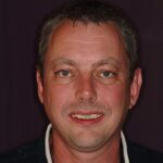 Smiling man before dental cleaning with visible discoloration.