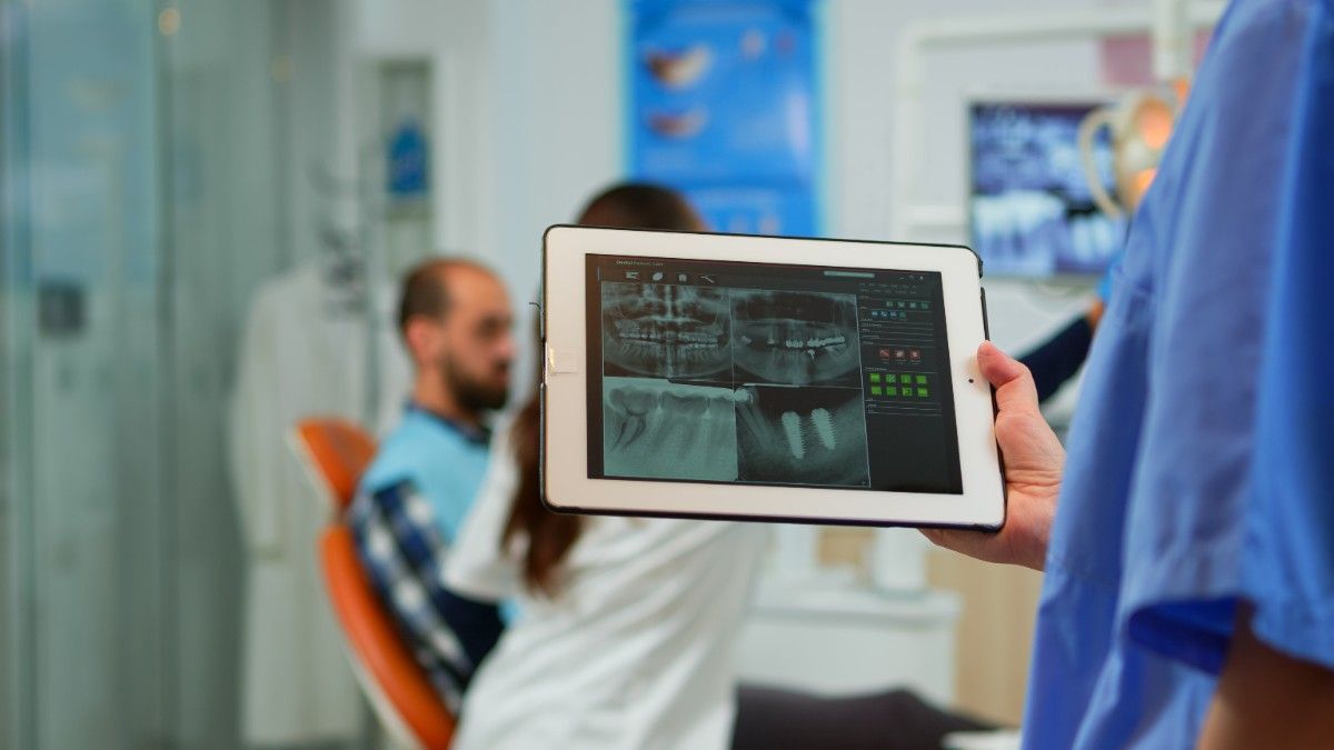 Dentist showing dental X-rays on tablet to patient