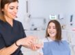 Dentist explaining dental crown treatment with tooth model to patient