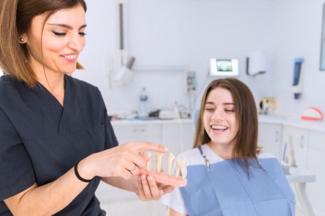 right-dental-crown-mooresville Dentist explaining dental crown treatment with tooth model to patient