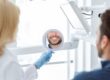 Dentist holding a dental mirror while a patient shows a bright smile.