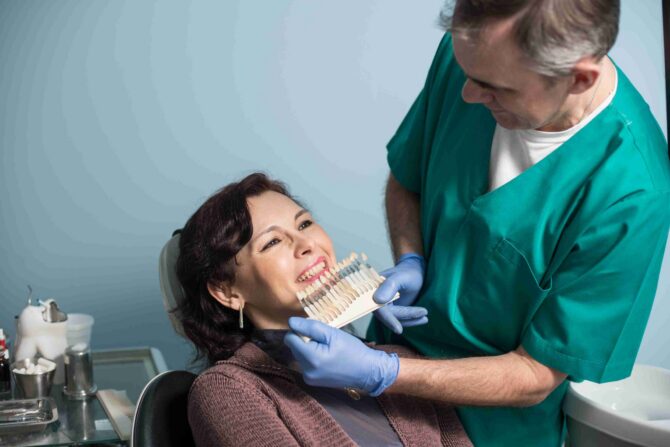 Dentist explaining tooth shade options to a smiling patient.