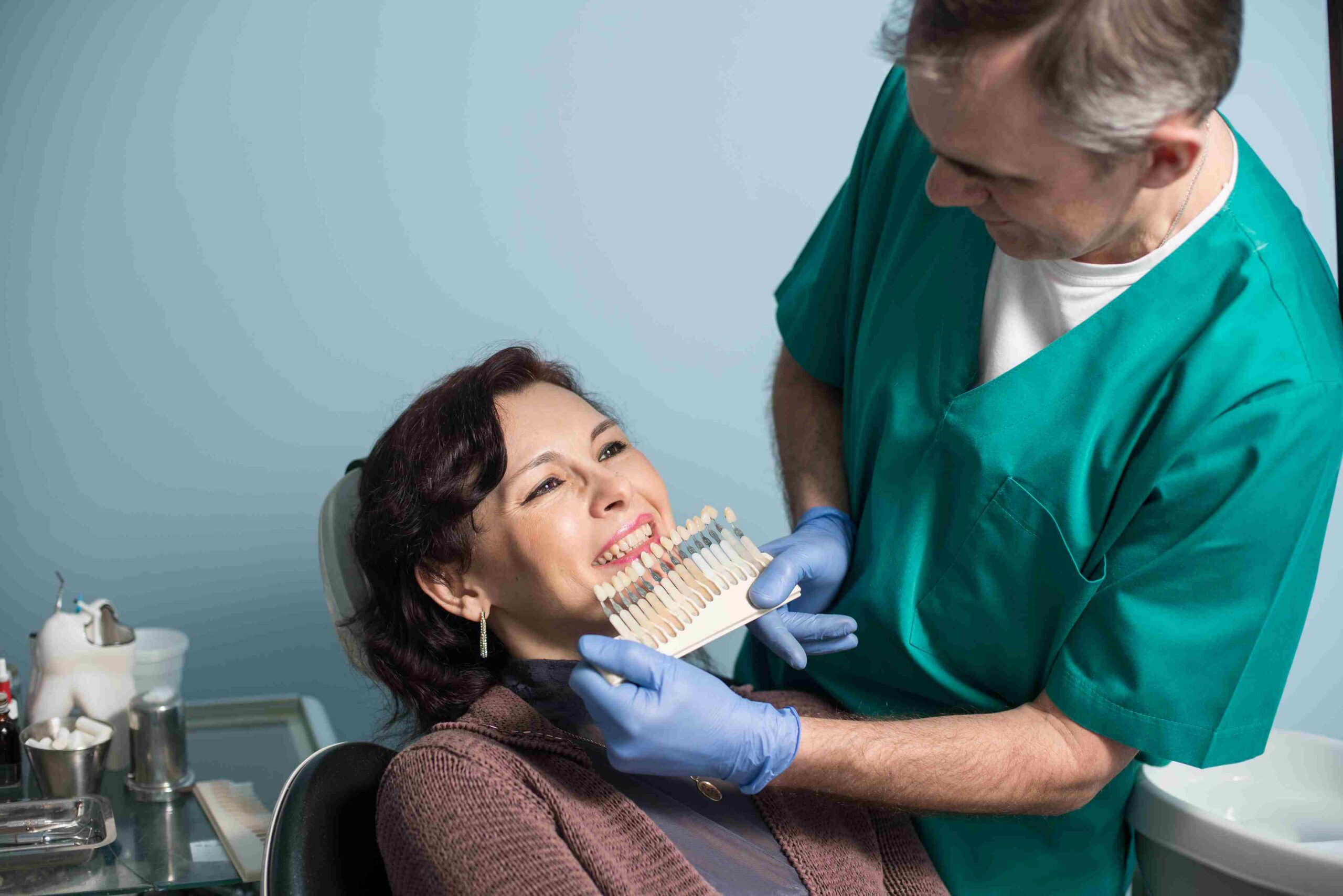Dentist explaining tooth shade options to a smiling patient.