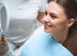 Patient smiling at her smile in a dental mirror.