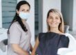 Dentist sitting beside a smiling patient in a dental chair during a routine dental examination.
