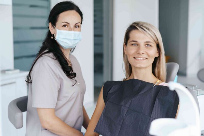 Dentist sitting beside a smiling patient in a dental chair during a routine dental examination.