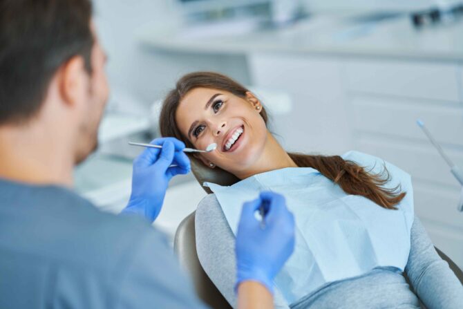 Dentist examining a smiling patient during a dental checkup.