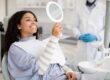 Smiling patient checking her smile in a mirror after dental treatment.